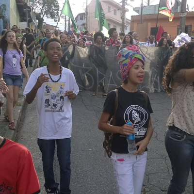 Primeira Marcha da Periferia da Brasilândia, movimento que ainda contece todo ano na semana da Consciência Negra, Novembro. A tradição dessa marcha foi iniciada dentro da ocupação da Escola Estadual Martin Egidio Damy. Na foto pode-se ver Thiago, já com turbante na cabeça, e a professora Flávia, que também oferece depoimento neste episódio. Acervo pessoal, Brasilândia, São Paulo. 2015.