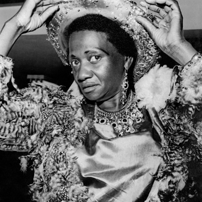 Carolina Maria de Jesus pronta para o carnaval com casaco feito com penas de galinha d’Angola que ela mesma confeccionou em 1963. Foto Sidney. Arquivo Público do Estado de São Paulo/Última Hora.